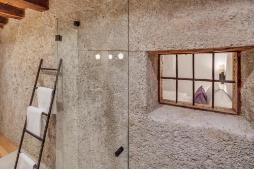 拉滕堡Boutiquehotel Rattenberg的石质浴室设有玻璃淋浴间和窗户