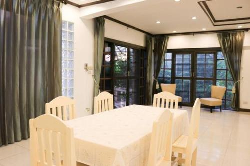 暖武里府Bed By Cruise Hotel At Samakkhi-Tivanont的一间配备有白色桌椅的用餐室