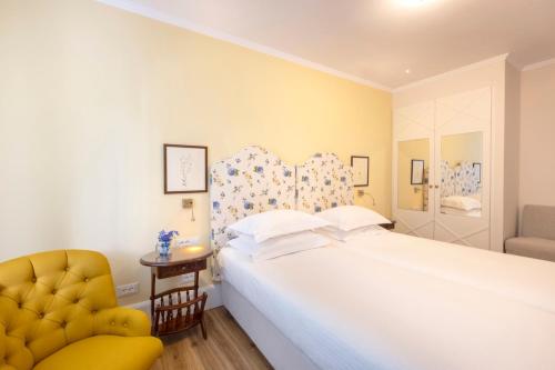 米克诺斯城科嫩尼公寓的卧室配有白色的床和黄色椅子