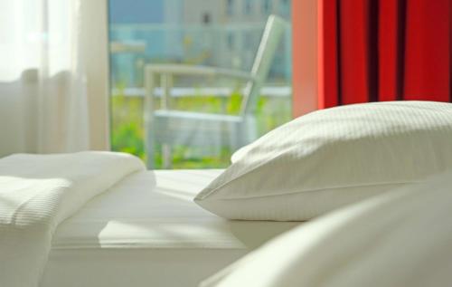 林茨林茨雷迪森公园客栈的白色的床、白色枕头和窗户