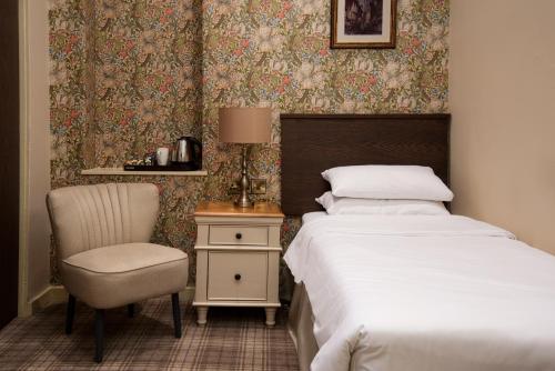 纳尔斯伯勒The Knaresborough Inn - The Inn Collection Group的一间卧室配有一张床、一把椅子和一张桌子