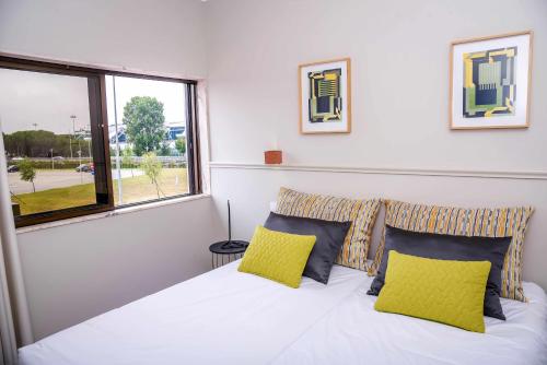 马亚Hotel Singular Porto Aeroporto的卧室配有白色床和2个黄色枕头