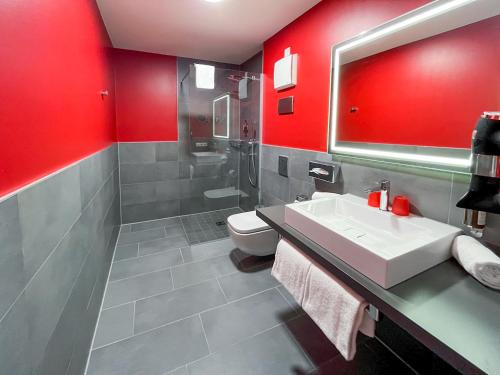 黑尔斯布鲁克DORMERO Hotel Hersbruck的浴室设有红色的墙壁、水槽和卫生间