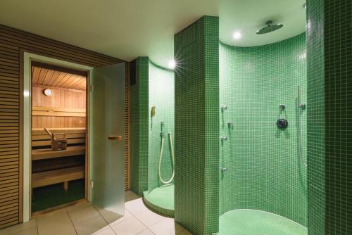 萨尔茨堡嘎斯霍夫布朗德斯塔特酒店的浴室设有绿色瓷砖墙壁和淋浴。
