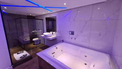 阿雷格里港Sense Motel的大型白色浴室设有浴缸和卫生间