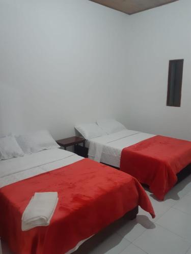 波帕扬Hotel Lili Popayán - Sede 2的客房内的两张床和红色床单