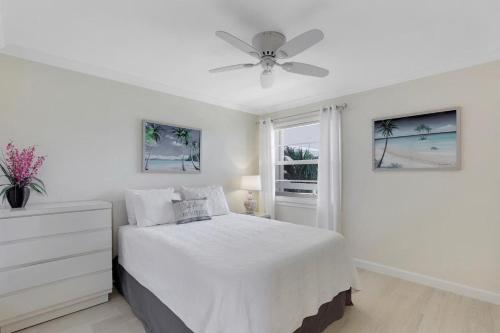 马可岛Moorings 302的白色卧室配有床和吊扇