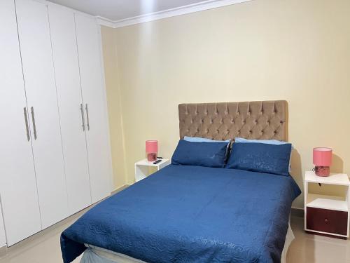 恩多拉Hibiscus Apartments的一间卧室配有蓝色的床和白色橱柜