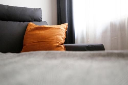 柏林Be in Berlin Apartments im Bergmannkiez的靠窗的床上的橙色枕头