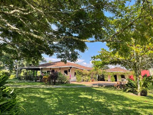 金巴亚MuchoSur Quimbaya的一座带绿色庭院和树木的房子