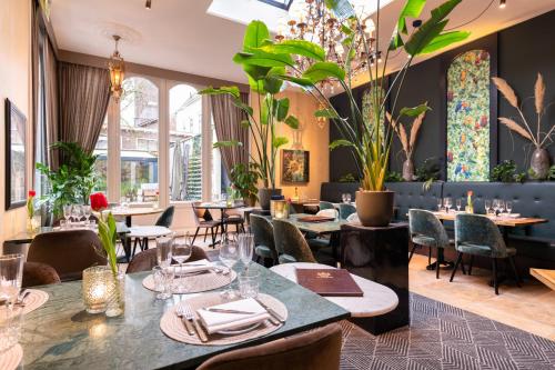 迪温特Grand Boutique Hotel-Restaurant Huis Vermeer的一间设有桌椅的餐厅,种植了植物
