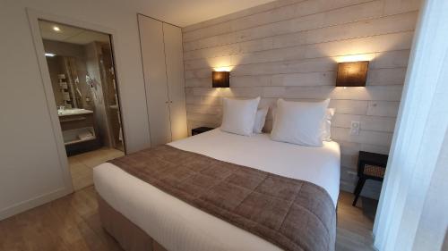 拉波勒Logis Hotel La Closerie的卧室配有一张带白色床单和枕头的大床。