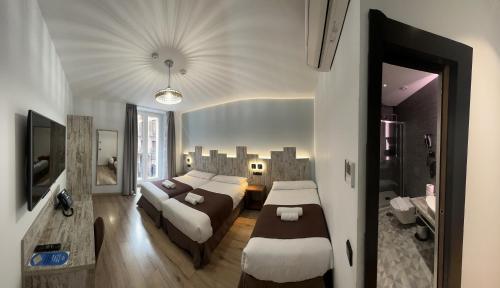 马德里Hostal Anton Martin的酒店客房,设有两张床和一张沙发