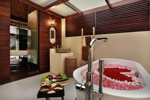 努沙杜瓦努沙杜瓦巴厘酒店的浴室配有装满红花的浴缸。
