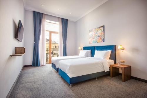 第比利斯Alma Boutique Hotel的酒店客房设有两张床和窗户。