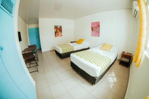 圣安德烈斯Viajero San Andres Hostel的一间卧室配有两张床和一张桌子及椅子