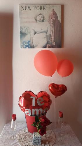LuqueHospedaje Luque的一张桌子,上面放着红色气球,还有一个花瓶,上面放着红心
