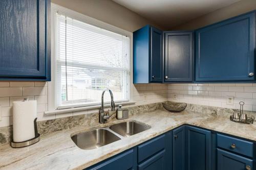里士满The Neighborhood House in Richmond的厨房配有蓝色橱柜、水槽和窗户。