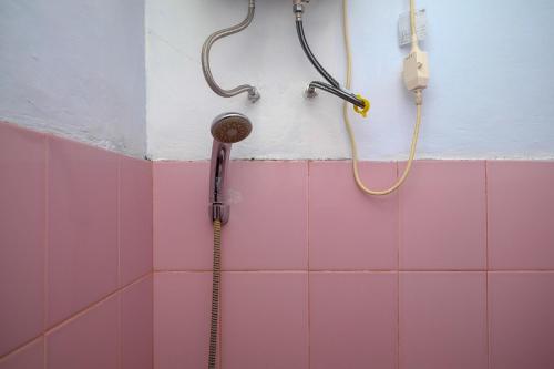 美娜多RedDoorz at Lapangan Bandara Sam Ratulangi Manado的浴室设有粉红色瓷砖和淋浴。
