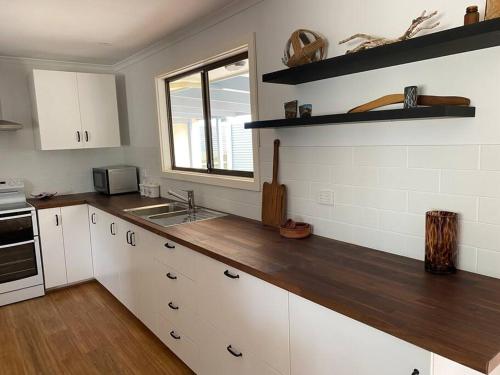 Port MinlacowieHardwicke Hideaway的厨房配有白色橱柜和木制台面