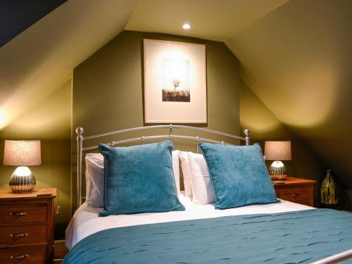 阿利士Cotlea East Cottage的一间卧室配有一张带蓝色枕头的床