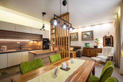 高塔特拉山Vila Kollár Vysoké Tatry的厨房以及带木桌和绿色椅子的客厅。