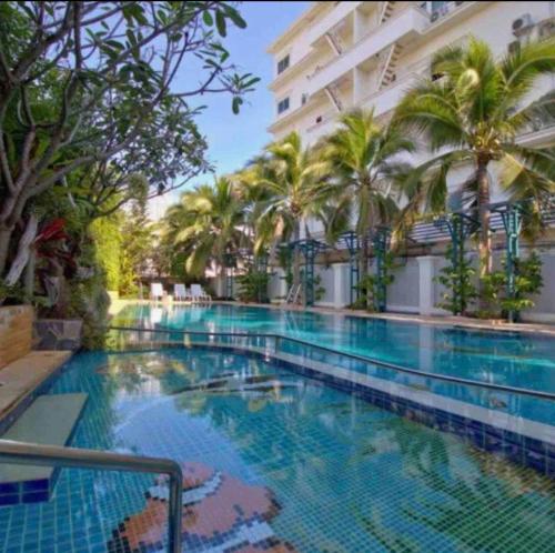 华欣华欣班客朗公寓酒店的一座棕榈树大型游泳池和一座建筑