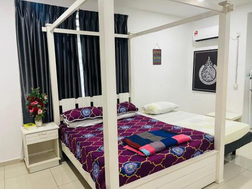 卢穆特NO 121 NAZIRIN HOMESTAY TMN DESA MANJUNG的一间卧室配有一张带紫色床单的天蓬床