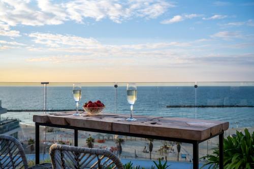 特拉维夫马克西姆3星级高级设计酒店的一张桌子,上面放着两杯葡萄酒和一篮水果