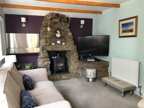 特鲁罗The Cottage Cox Hill Chacewater的客厅设有石制壁炉和电视。