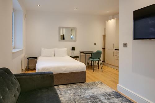 史云顿Swindon Apartments by Charles Hope的一间卧室配有一张床、一张沙发和一台电视。
