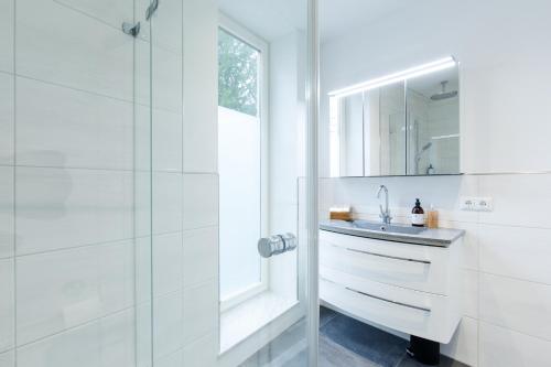 萨尔茨堡Mozart's Garden Villa的白色的浴室设有水槽和淋浴。