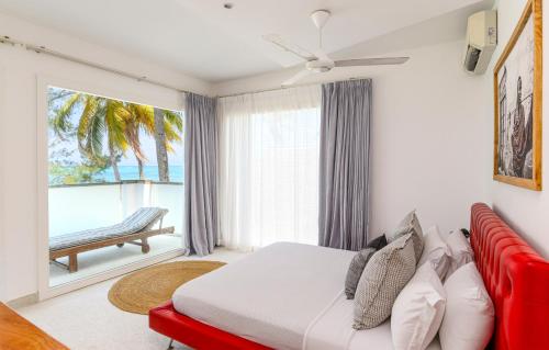 吉汶瓦Imani Penthouse - Private Beachfront apartment with Spectacular Ocean Views的一间卧室配有一张床和一张红色的沙发