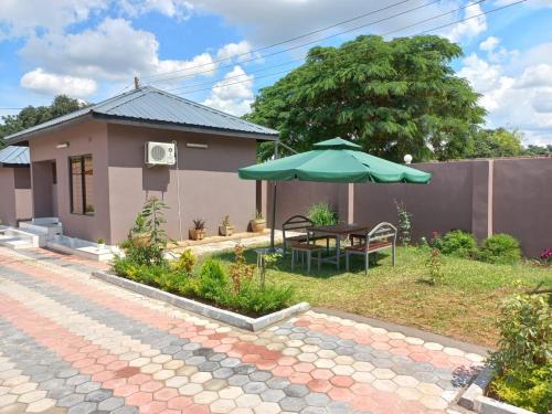 利文斯顿Kasuda three bedrooms house in Livingstone的院子里带桌子和雨伞的房子