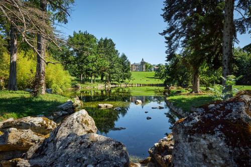 LagardeChâteau de Sibra的一座树木繁茂的公园内的池塘和一座城堡的背景