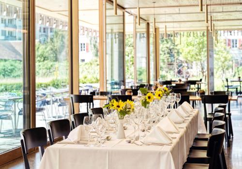 巴塞尔ODELYA Hotel & Naturgarten Basel City的餐厅里一张长桌子,上面有黄色的花