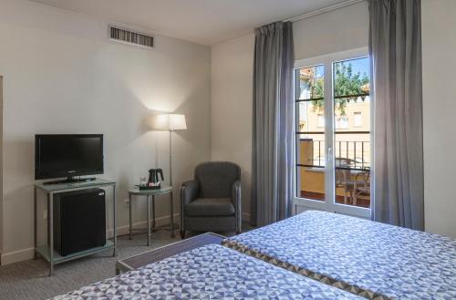 科尔多瓦Hotel Macià Alfaros的一间卧室设有一张床、一台电视和一个窗口。