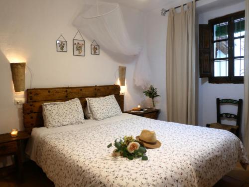 阿尔卡拉拉雷亚尔Cortijo Rural La Gineta Alcalá la Real的一间卧室,床上有帽子和鲜花
