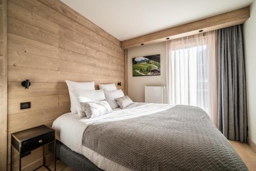 莱热Apartment Kanoko Les Gets- BY EMERALD STAY的一间卧室设有一张带木墙的大床