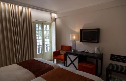 奥比多斯Josefa D`Obidos Hotel的酒店客房设有两张床、一张桌子和一台电视。