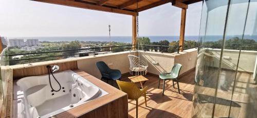 纳哈里亚Sea view apartment with Jacuzzi near beach的浴缸位于带椅子的阳台