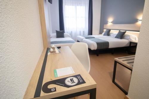 布尔戈斯Alda Puerto Seco的酒店客房设有两张床和一张带标志的桌子。