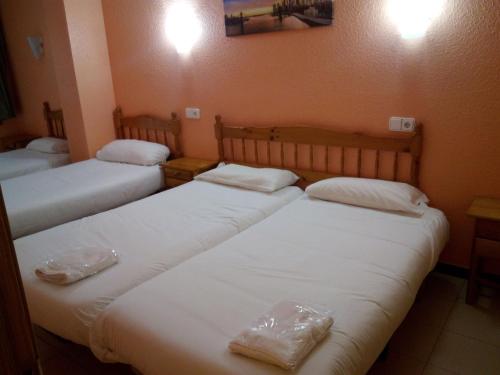 帕斯底拉卡萨埃尔斯艾维斯公寓酒店的配有白色床单的客房内的三张床