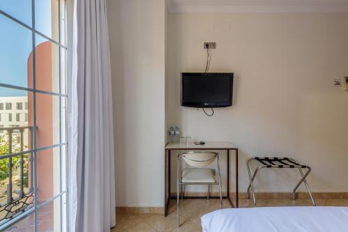 马拉加H-A Hotel Trebol的一间卧室配有电视、桌子和椅子