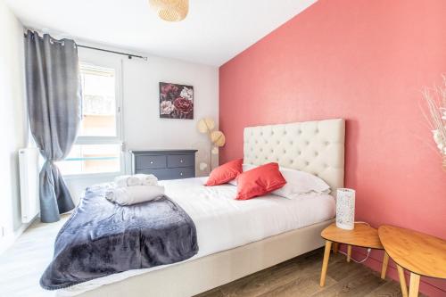 克莱蒙费朗L'adorable Confort & Central的卧室拥有粉红色的墙壁,配有一张带红色枕头的床