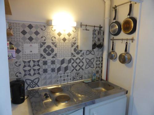 图尔Studio calme au coeur de Tours的一间带水槽和瓷砖墙的厨房