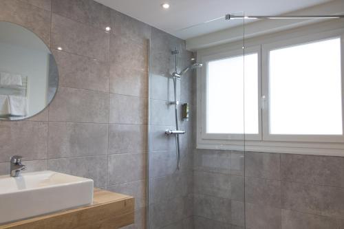 瓦讷Logis Golfe Hotel的带淋浴、盥洗盆和镜子的浴室