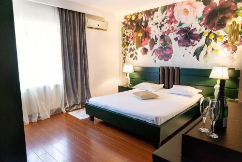 布加勒斯特Phoenicia Suites Baneasa的卧室配有一张挂有花卉画的床铺。