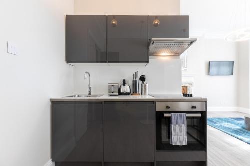 伦敦Air Conditioned Apt High St Kensington的厨房配有黑色橱柜和水槽