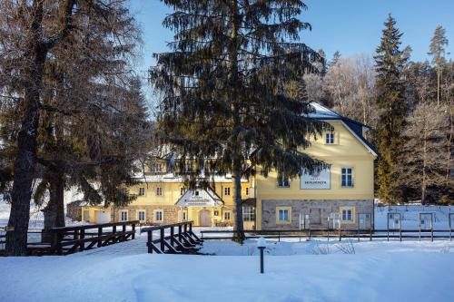 阿德尔什帕赫Skalní Mlýn Adršpach的一座黄色的大建筑,雪中设有栅栏